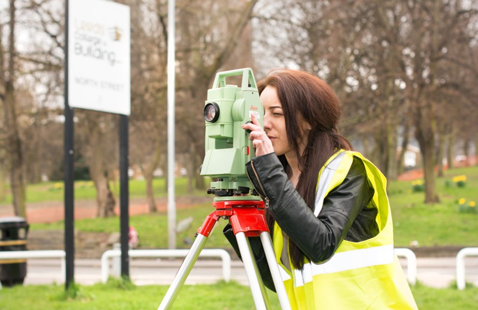 Land surveying student using survey equipment