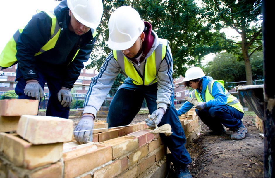 Three apprentices laying bricks 