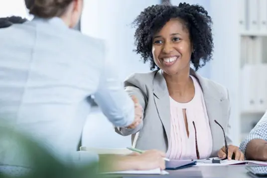 two people greeting each other with a handshake in an office