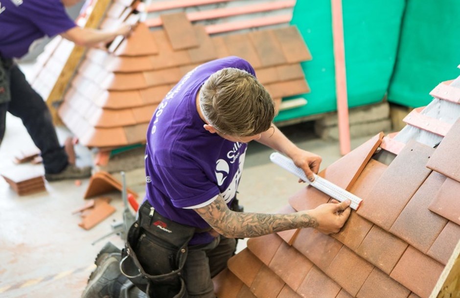 A roofing apprentice practicing laying roof slates in a workshop 